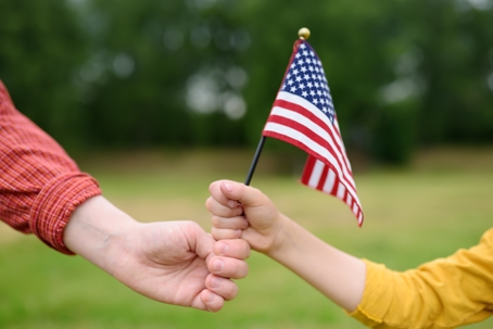 adult handing US flag to child