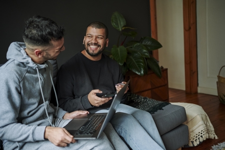 same-sex couple looking at laptop on couch