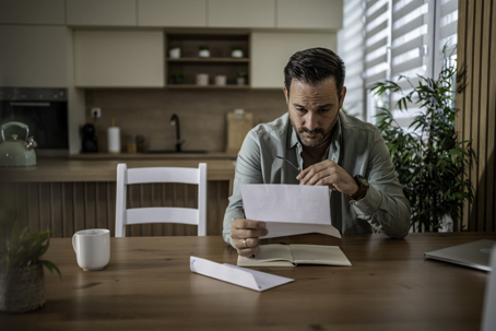 troubled man reading a letter at home